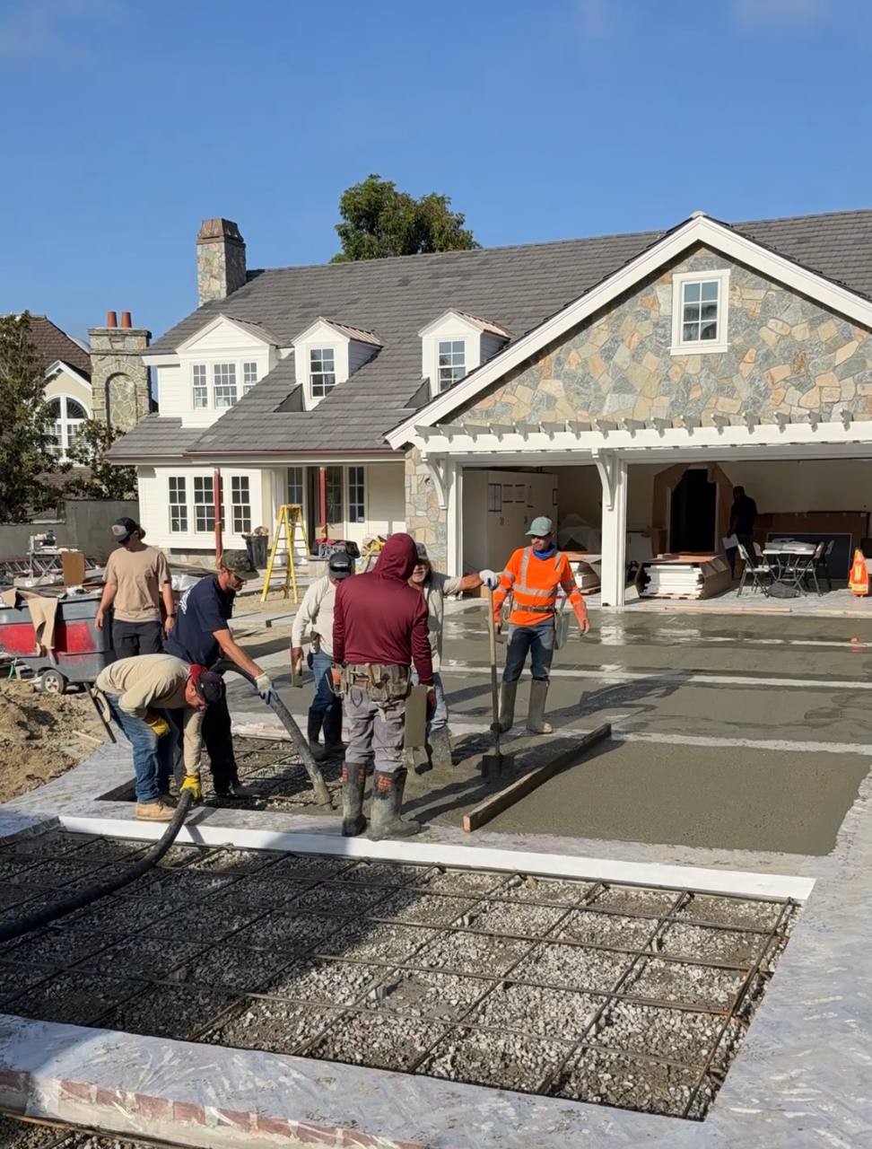 Scott's Concrete Pumping crew finishing a residential pea gravel concrete pour with the pump line visible in the foreground.